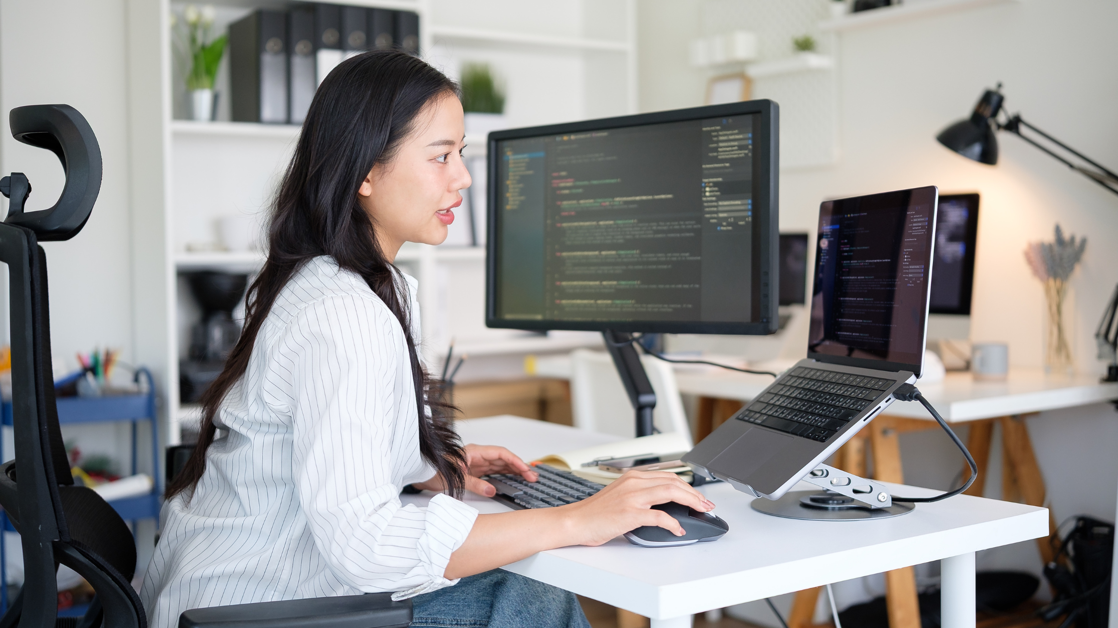 Woman using a notebook computer with external monitor attached